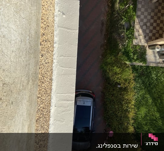 מבט מלמעלה על מכונית חונה ליד קיר בניין